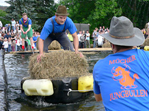 Auf einem Kunststoff-Flo wird ein Mitspieler der 'Mcher Jungbullen' mitsamt eines Heuballens ber ein Wasserbecken gezogen