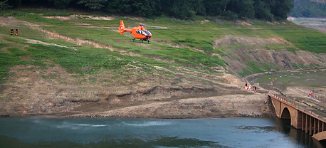 Vom freigelegten Hang zwischen Wasserlinie und Baumgrenze startet der orangefarbene Rettungshubschrauber ber die Derenbachtalbrcke hinweg